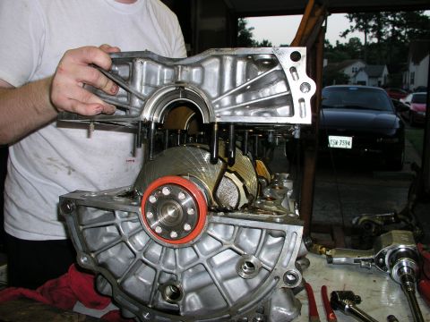 1996 Ford Probe - Mechanic works on engine block and crankshaft assembly, with a black car visible in the background.