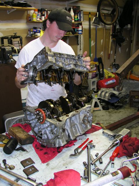 1996 Ford Probe - Mechanic works on engine block and crankshaft assembly in a garage setting.