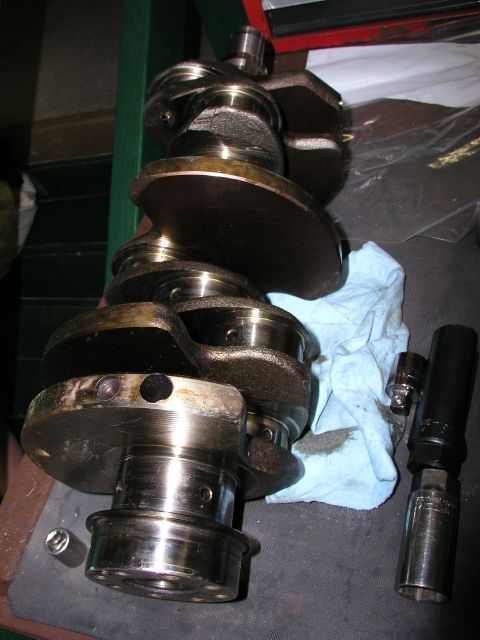 1996 Ford Probe - A crankshaft sits on a workbench next to a rag and some socket wrenches.