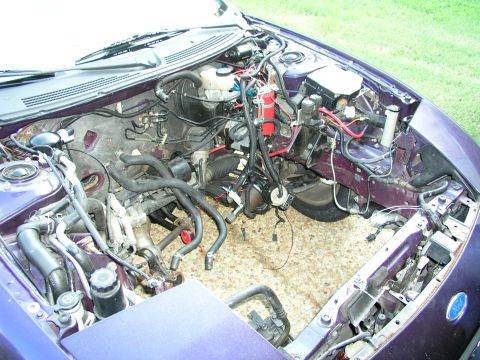 1996 Ford Probe - The engine bay of a purple car is shown with various hoses and wires disconnected during a rebuild.