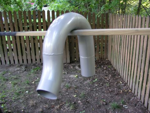 1996 Ford Probe - A bent exhaust pipe is supported by a wooden dowel in front of a backyard fence.