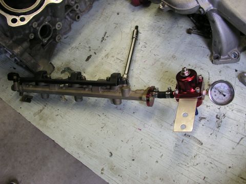 1996 Ford Probe - A fuel rail assembly with a red adjustable fuel pressure regulator and a pressure gauge is shown, likely for a turbo motor rebuild.