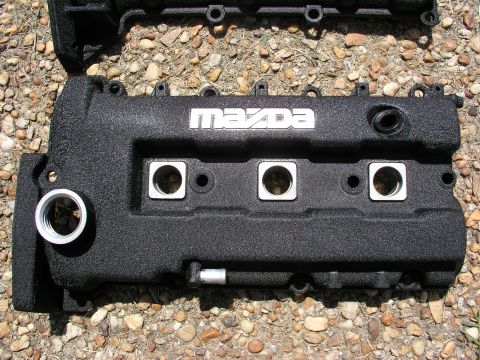 1996 Ford Probe - Close-up of a black textured Mazda valve cover with silver lettering and mounting holes.