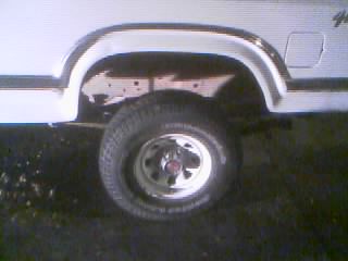 1986 Ford Bronco - Close-up of the rear wheel well on a white vehicle, showing some wear and tear.