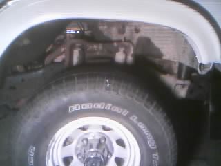 1986 Ford Bronco - Front wheel well detail of a truck, focusing on the tire and suspension.