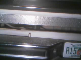 1986 Ford Bronco - Close-up of a vehicle's rear bumper and license plate, showing some custom trim.