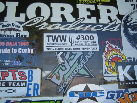 1990 Ford Bronco - Off-road racing decals cover a window, including a TWW #300 Moss Brothers 2005 Score Baja 1000 sticker.