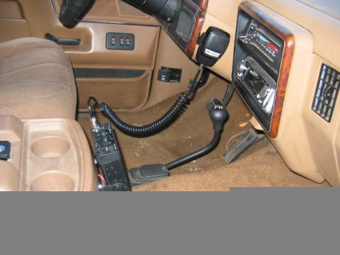 1990 Ford Bronco - The interior of a vehicle shows a CB radio and microphone installed, with the gear shifter and part of the dashboard visible.
