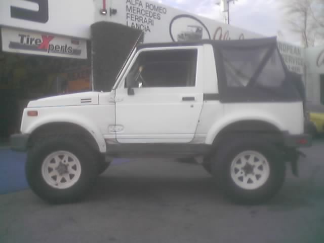 White Suzuki Samurai parked outside a tire shop
