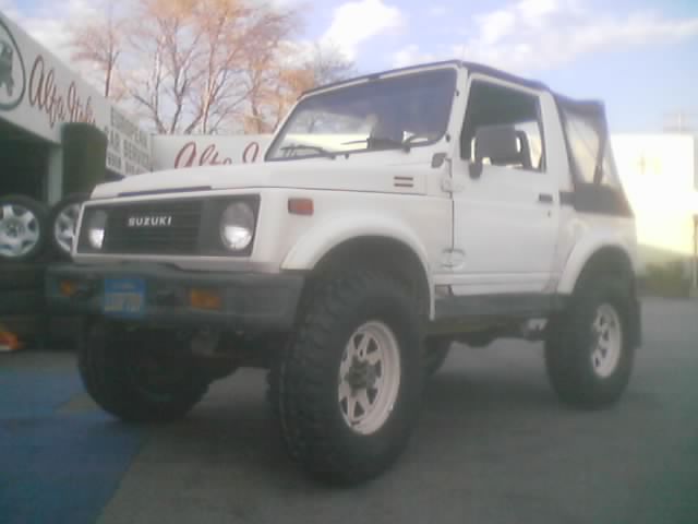 White lifted Suzuki Samurai parked on blue pavement