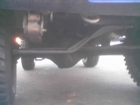 1990 Ford Bronco - Underbody view of a lifted vehicle's front axle, control arm and tires seen from below.