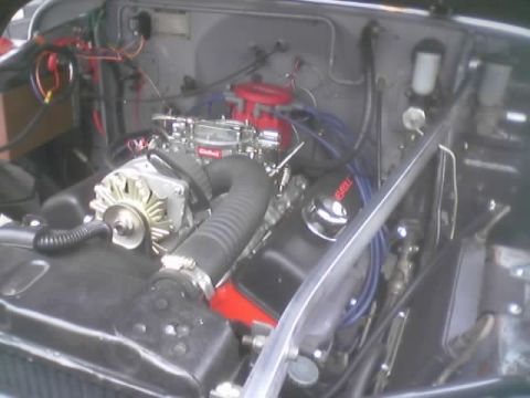 1990 Ford Bronco - engine bay showing an Edelbrock carburetor, chrome alternator and blue plug wires in a vintage vehicle.