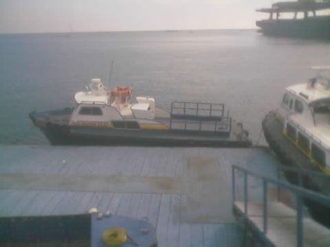 1990 Ford Bronco - Two white-and-yellow utility boats float beside a wooden dock on calm water near a larger vessel.