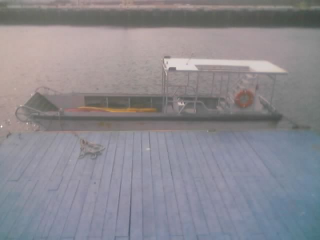 Gray covered launch boat moored beside a wooden dock