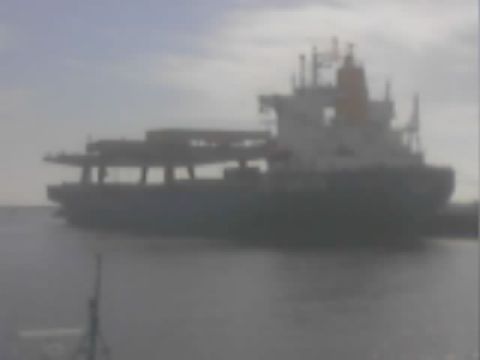 1990 Ford Bronco - large blue-hulled bulk cargo ship with deck cranes moves across hazy gray water.