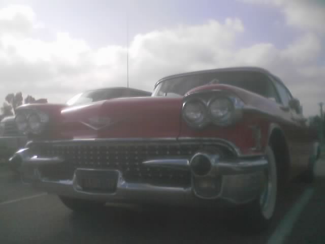 Low front angle of a red 1958 Cadillac under a cloudy sky