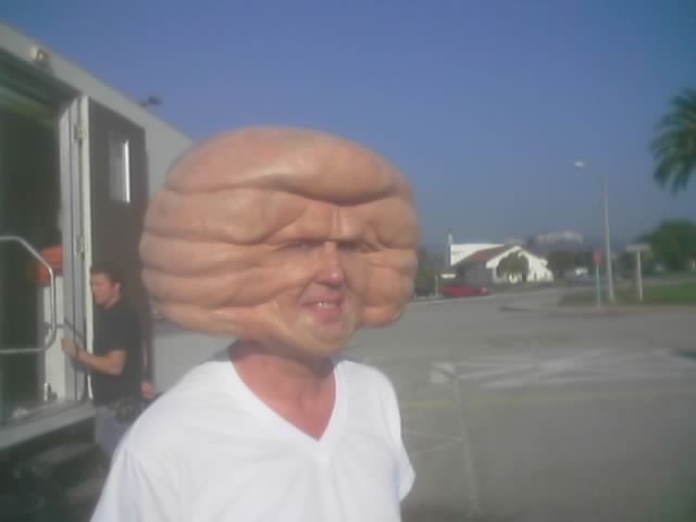 Man wearing an oversized wrinkled rubber old-man mask outdoors