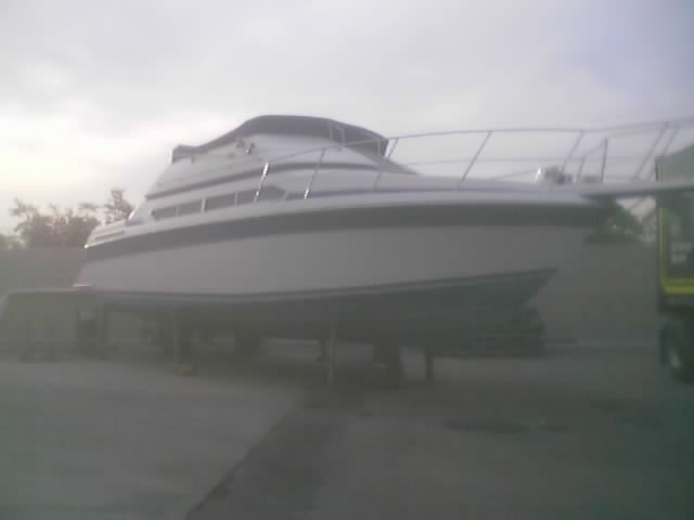 White and blue boat on stands, side view, overcast sky