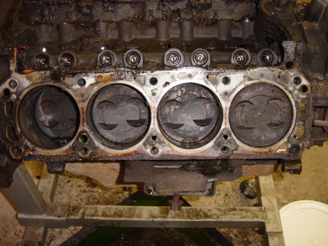 Disassembled V8 engine block deck with carbon-coated piston tops