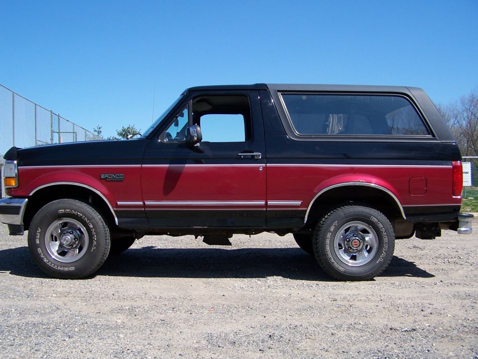 Two-tone black and red Ford Bronco SUV, side view. Chrome trim and wheels