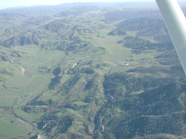 Aerial view of rolling green hills and valleys with a road winding through
