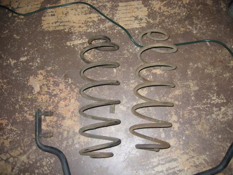 1985 Ford LTD Crown Victoria - Two coil springs and a sway bar end link are shown, likely for a vehicle's suspension system.