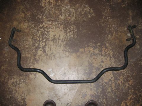 1985 Ford LTD Crown Victoria - A sway bar, likely from a vehicle's suspension system, lies on a textured concrete surface.