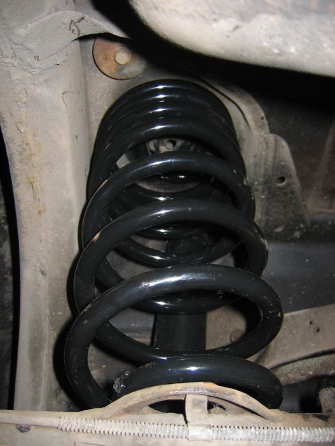 1985 Ford LTD Crown Victoria - Close-up view of a vehicle's rear suspension system, focusing on the coil spring and shock absorber.