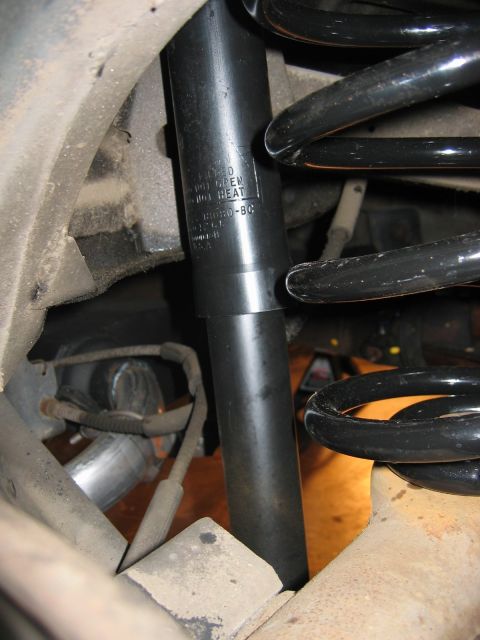 1985 Ford LTD Crown Victoria - Close-up view of a rear shock absorber and coil spring, with some text visible on the shock body.