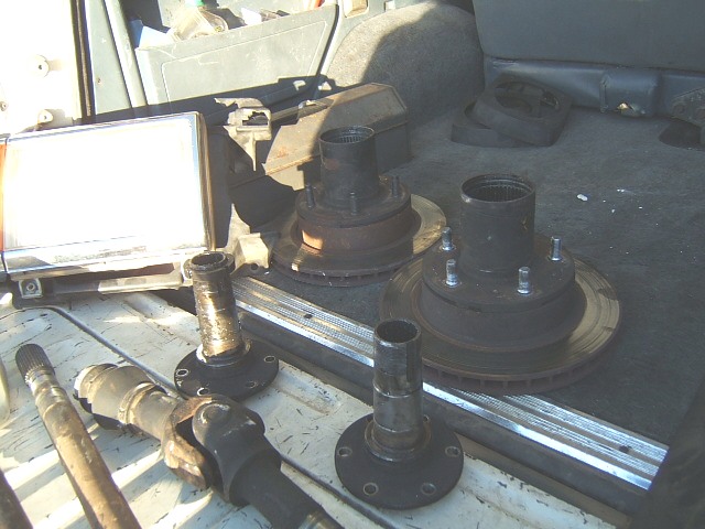 Used hub and rotor assemblies, spindles and driveshaft laid out in a truck bed