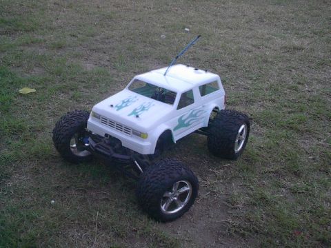 1993 Ford Bronco - This remote control monster truck features a white body with green flame graphics and oversized off-road tires.