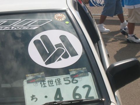 1986 Ford Bronco - A close-up view of a car's windshield shows a large circular sticker and a Japanese license plate with smaller stickers attached.