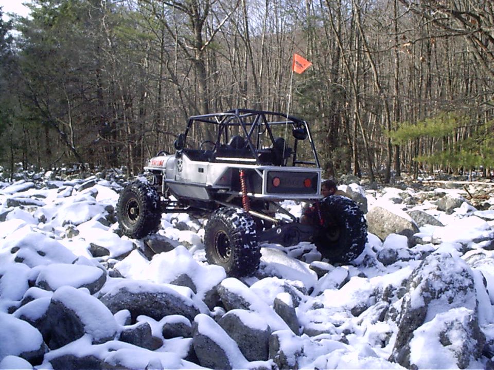 Off-road buggy with roll cage and large tires on snowy rocks