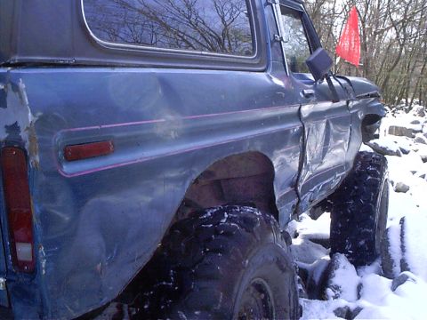 1989 Ford F-350 - This heavily damaged blue SUV is equipped with large off-road tires and is seen in a snowy environment.