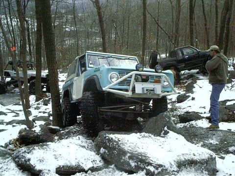 1989 Ford F-350 - This modified SUV navigates a challenging snowy trail with other vehicles in the background.