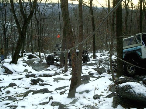 1989 Ford F-350 - Multiple off-road vehicles navigate a challenging, snow-dusted woodland path.