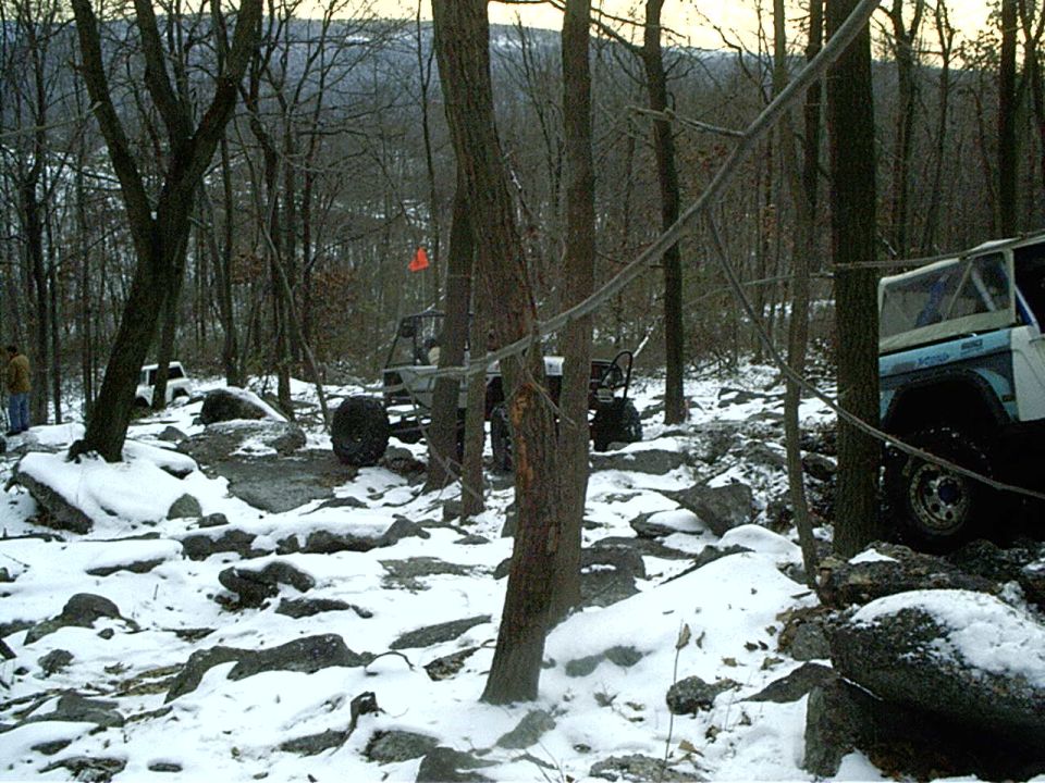 Blue and white Ford Bronco on rocky, snow-covered trail
