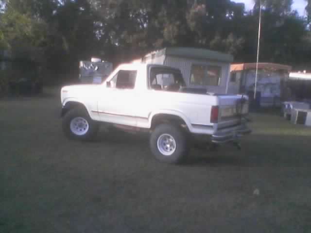 White SUV with lifted suspension and off-road tires parked on grass