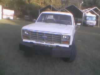 1986 Ford Bronco - A white Ford truck with a body lift is parked outdoors, with a recreational vehicle visible in the background.