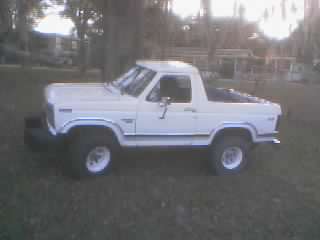 1986 Ford Bronco - This white SUV has a lifted suspension and is parked outdoors on a grassy area.