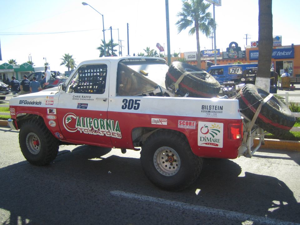 Side view of red and white #305 California Tomatoes off-road race truck