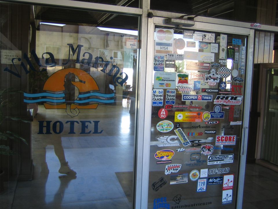 Glass hotel door lettered Villa Marina Hotel covered in racing stickers