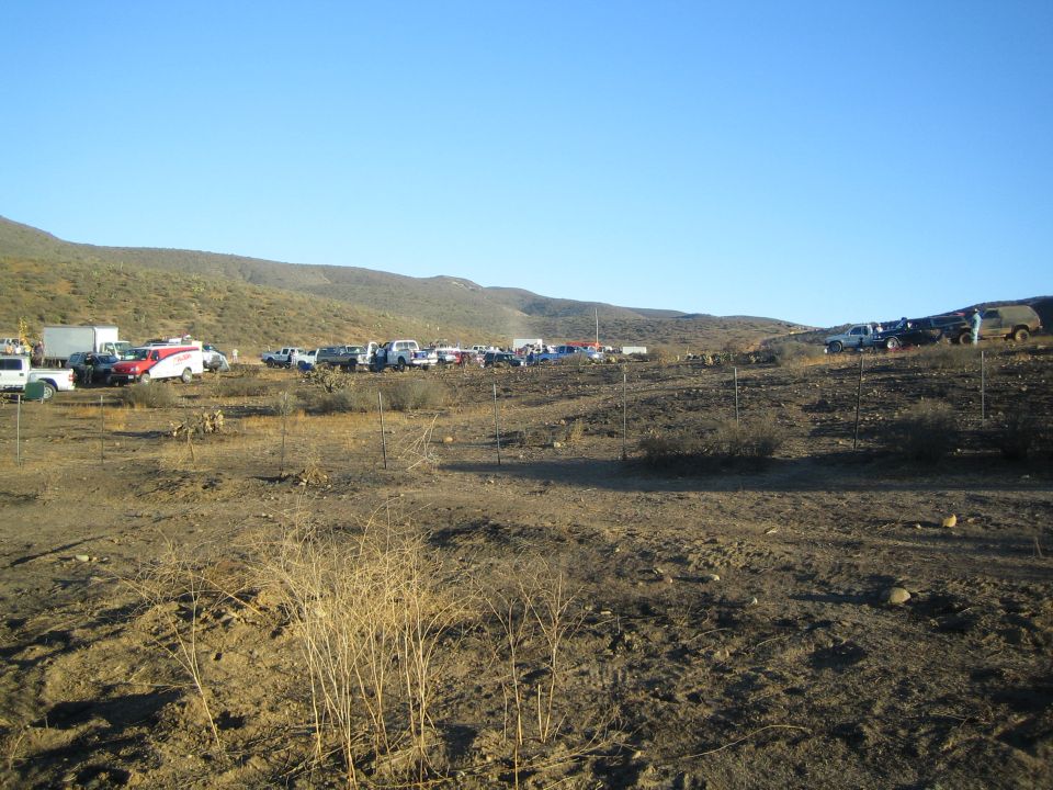 Cluster of parked vehicles and RVs in a barren desert valley