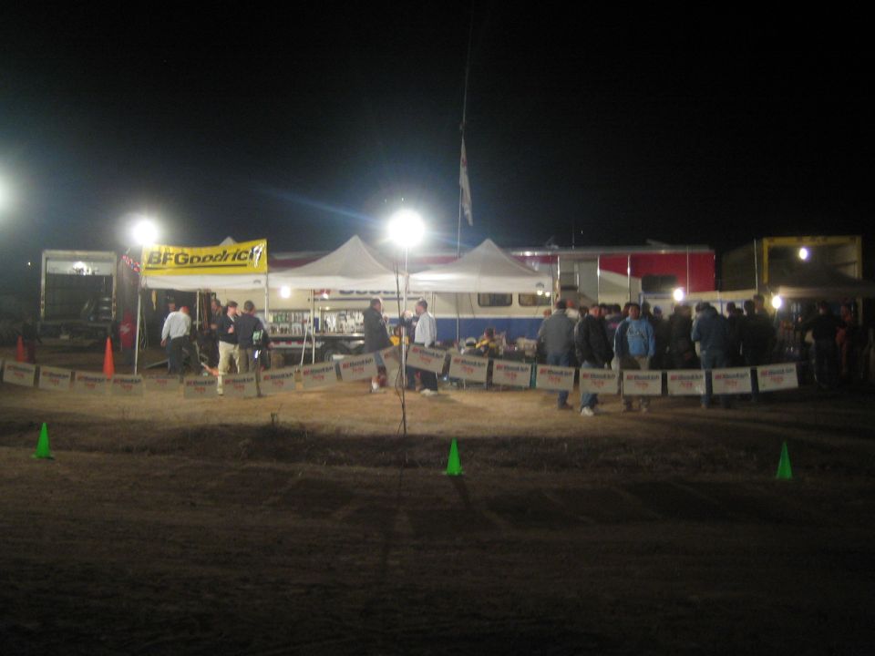 Floodlit race pit tents and crowd with BFGoodrich banner at night