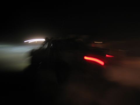 1990 Ford Bronco - heavily blurred night photo showing streaking white headlight and red taillight trails from a moving vehicle.
