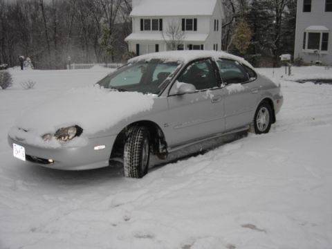 1999 Ford Taurus - A silver sedan sits covered in snow on a winter day.