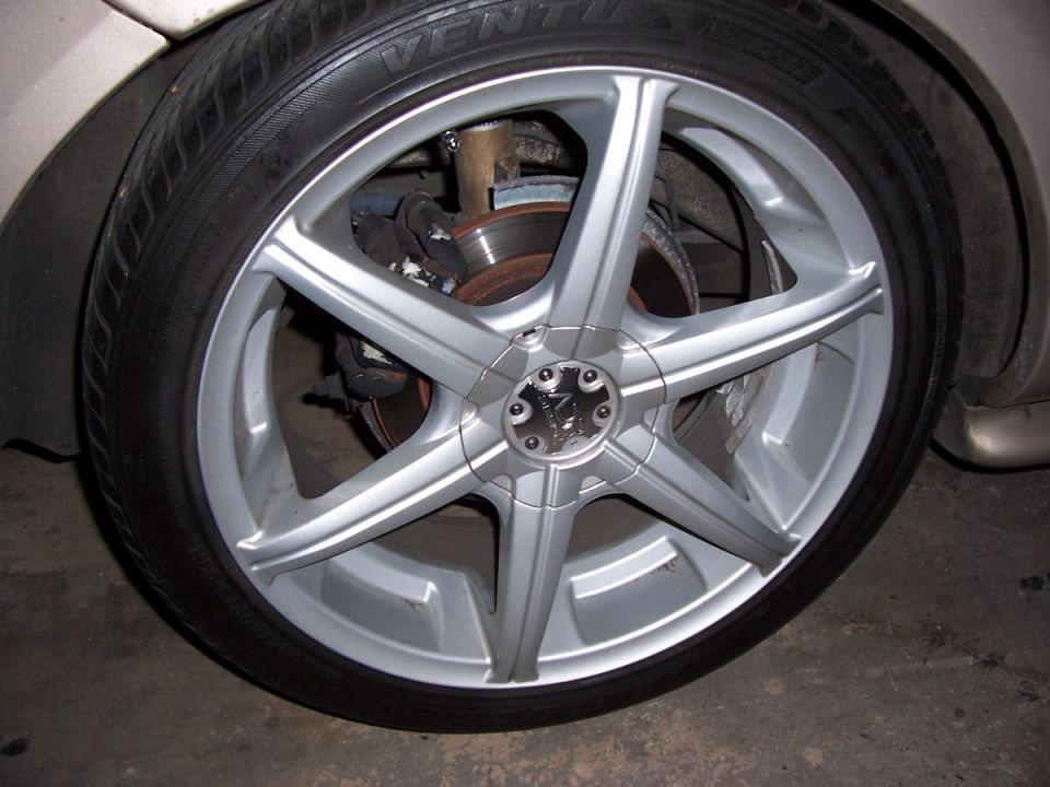 Silver five-spoke aftermarket wheel with a visible brake rotor and caliper