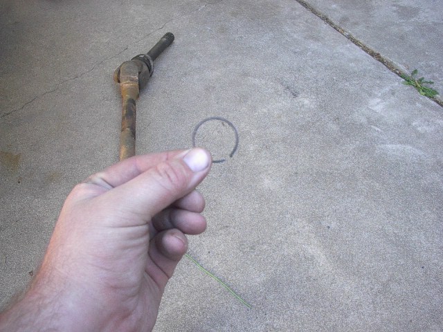 Hand holding snap ring near driveshaft joint
