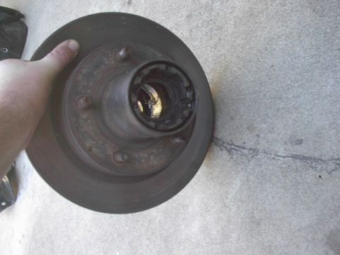1993 Ford Bronco - A close-up view of a vehicle's brake rotor and hub assembly, held by a person's hand.