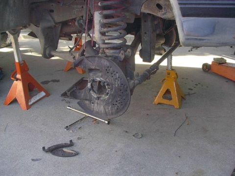1993 Ford Bronco - The vehicle's front suspension and brake system are disassembled and supported by jack stands.